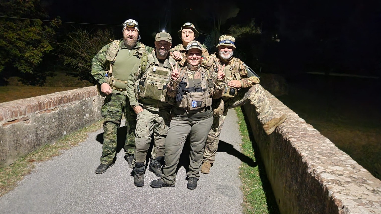 Cinque componenti degli ELFI riuniti su un ponte in pietra durante l’escursione notturna a Calci