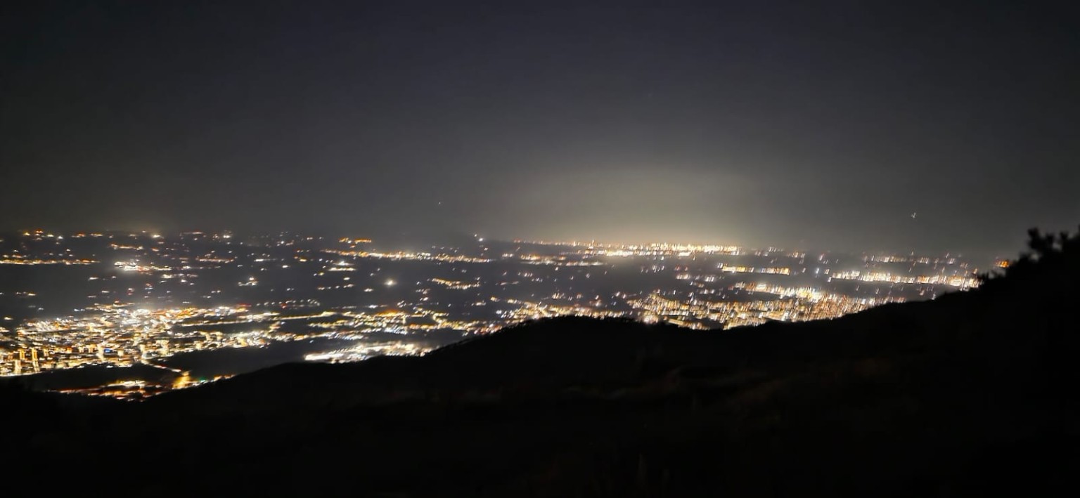Ampio panorama notturno della valle con la sagoma del pendio in primo piano