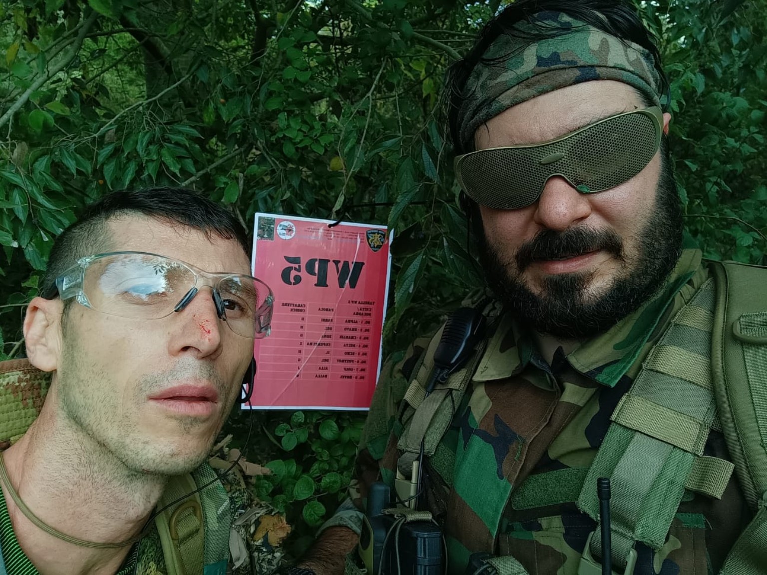 Due giocatori ELFI in equipaggiamento mimetico e con occhiali protettivi davanti alla scheda del WP5 nel bosco