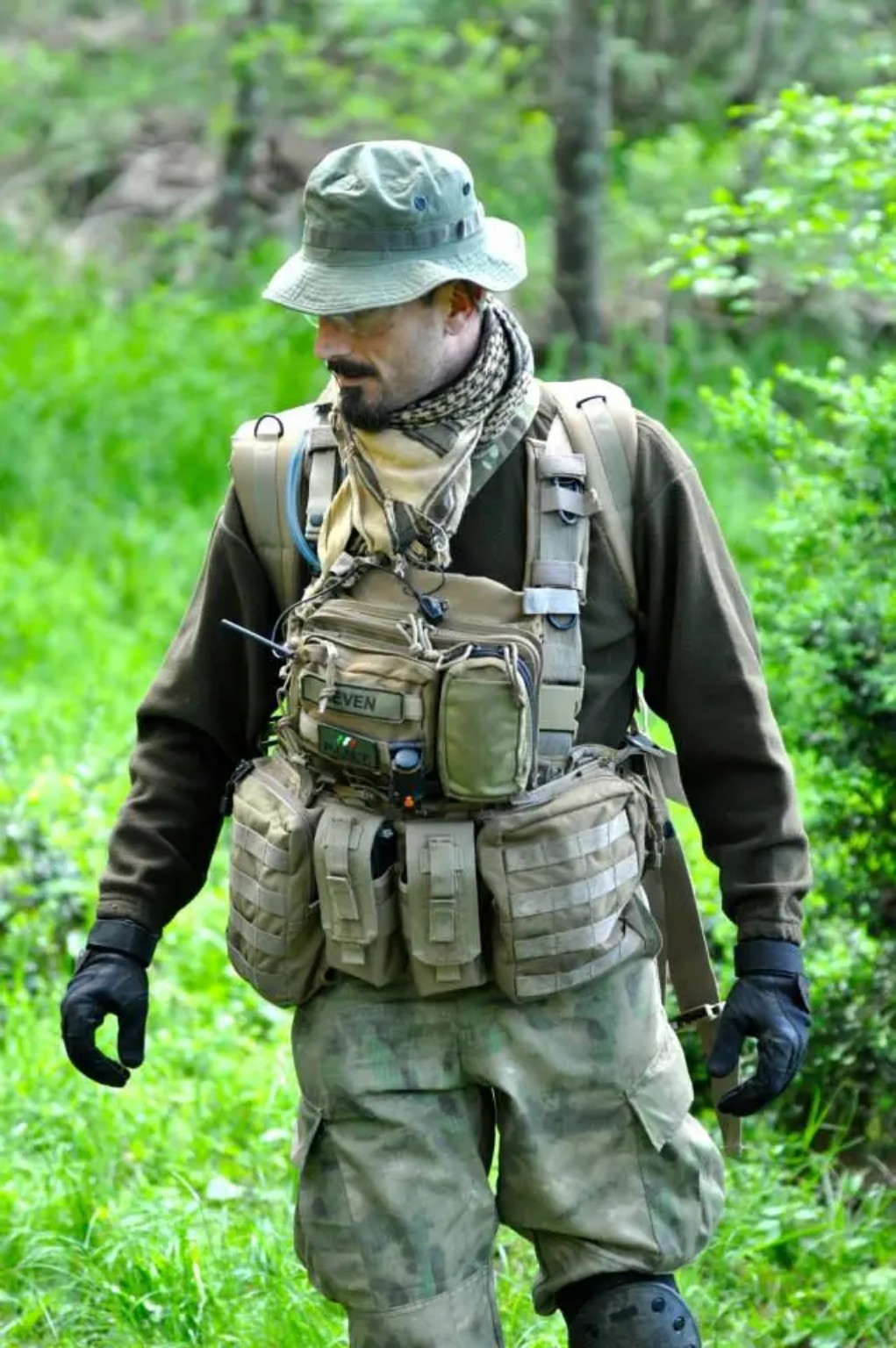 Giocatore softair con equipaggiamento radio durante un game nel bosco
