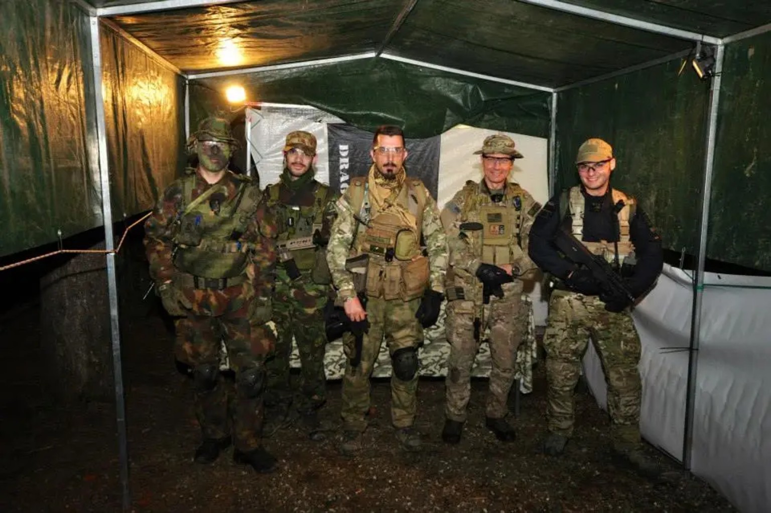 Gruppo di cinque giocatori softair equipaggiati sotto una tenda da campo